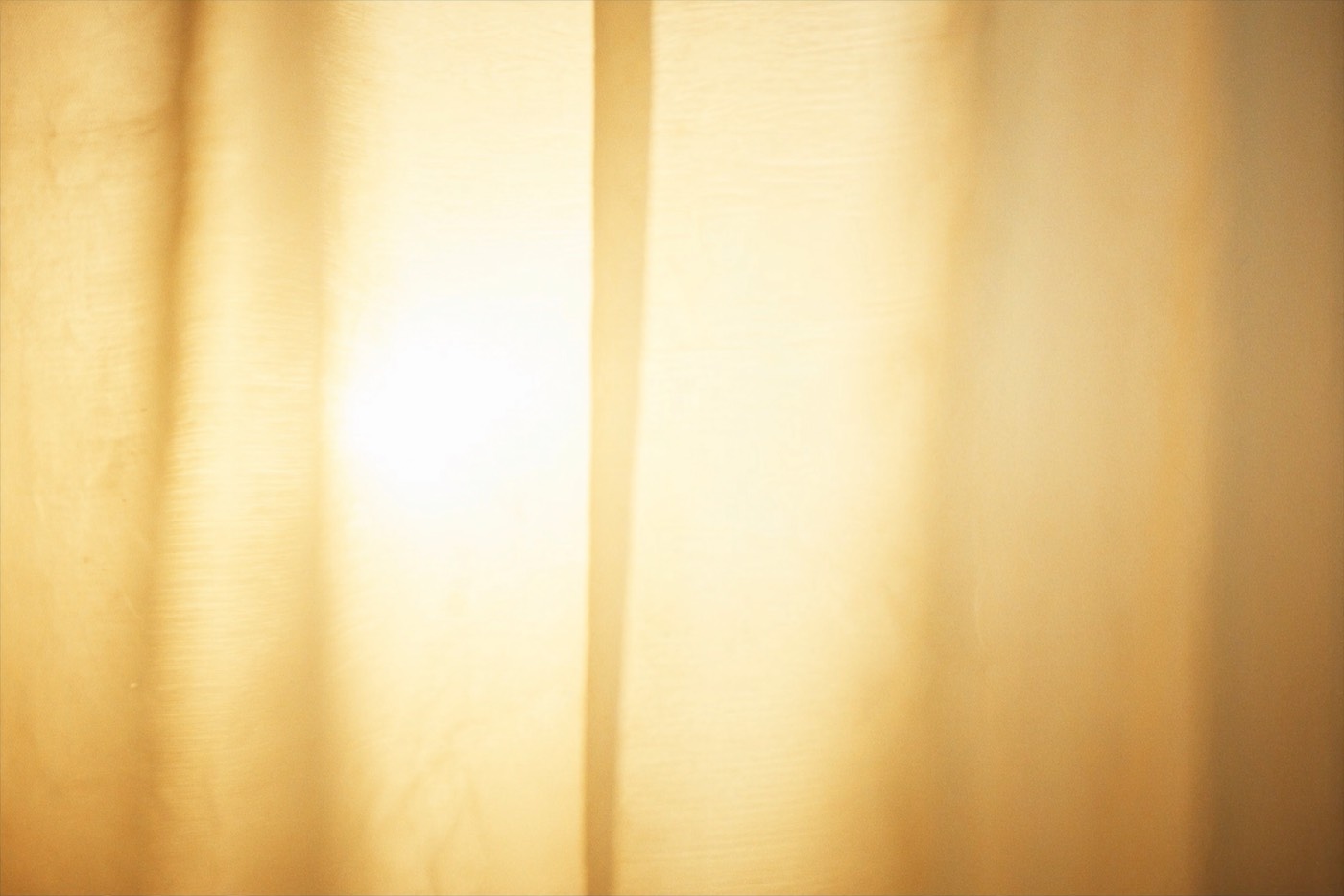 Soft golden morning light glowing through a sheer curtain