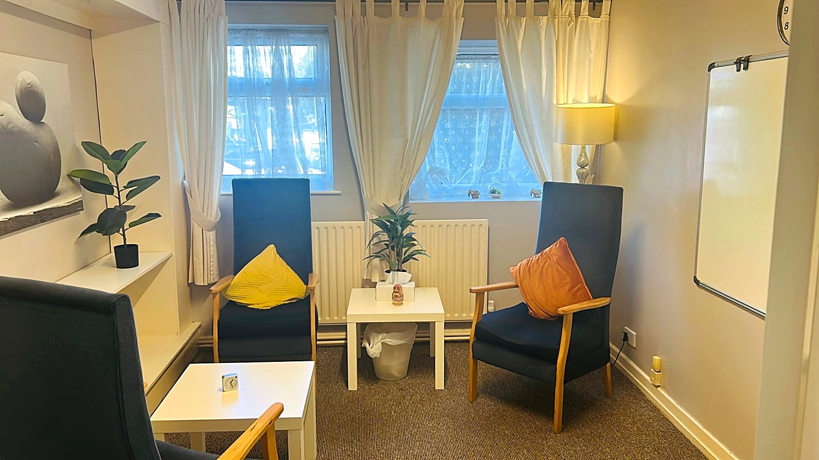 A warm, comfortable counselling room with two armchairs in soft morning light
